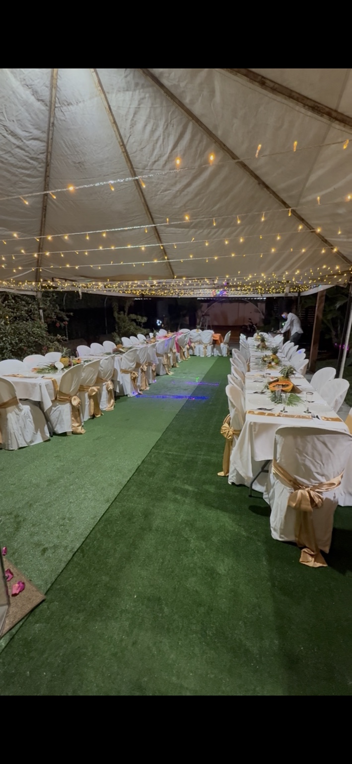 Montaje de celebración bajo carpa con mesas, luces y decoración dorada