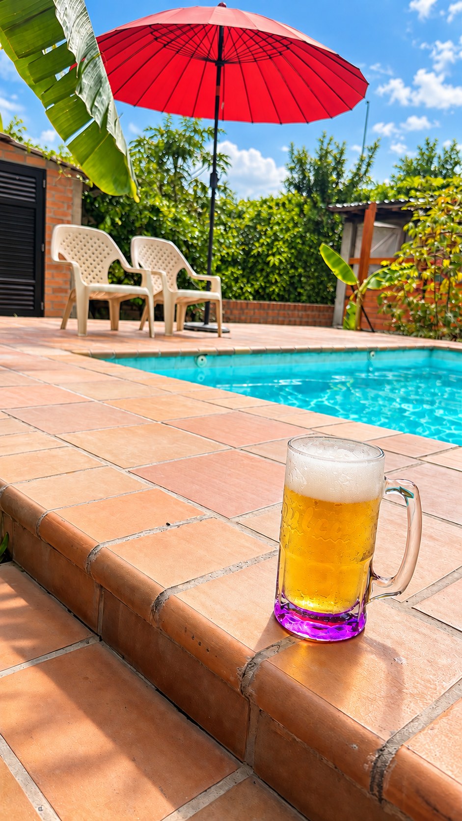 Bebida junto a la piscina bajo una sombrilla roja en La Casita de Campo